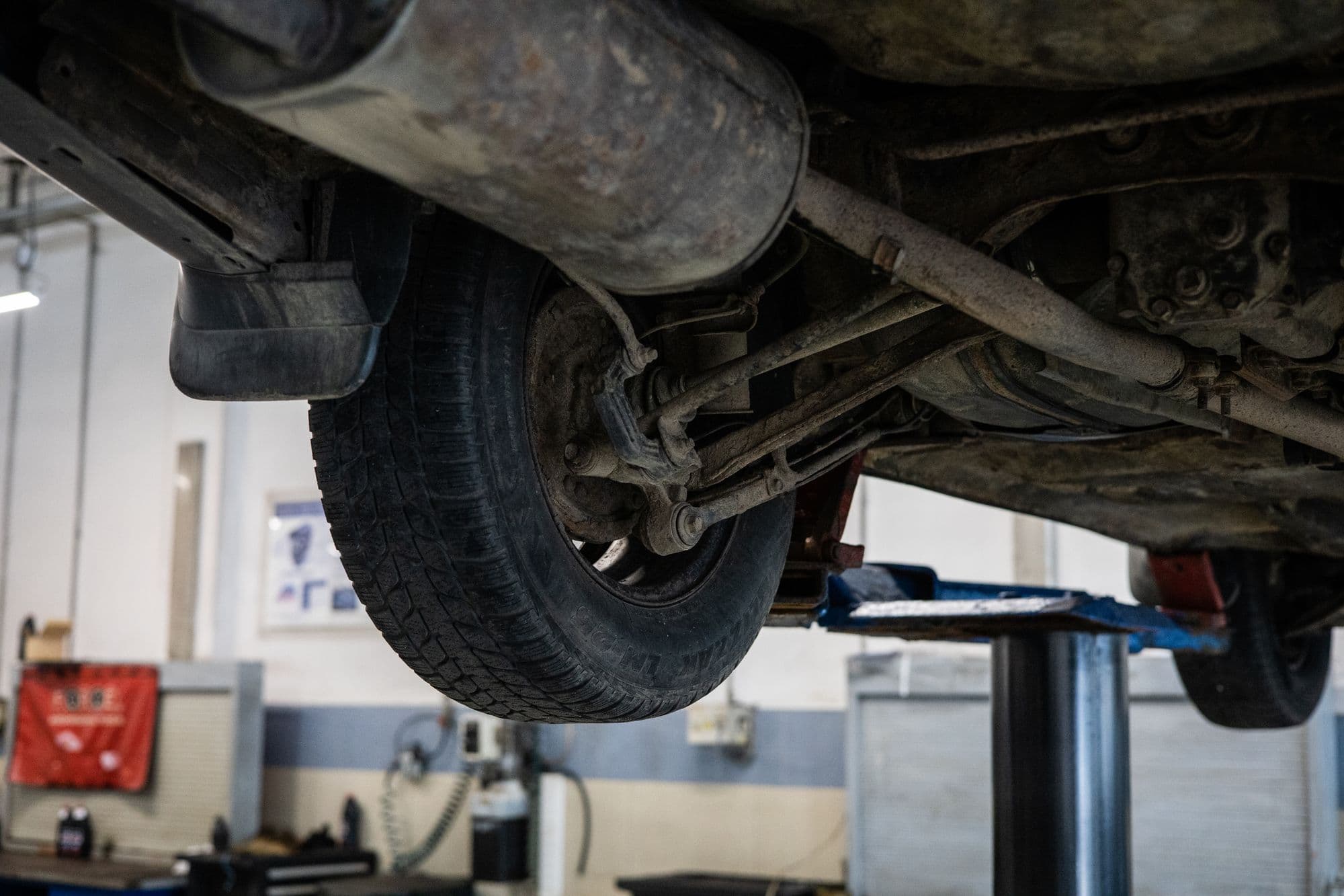 The underside of a car on a lift, showing the exhaust and suspension