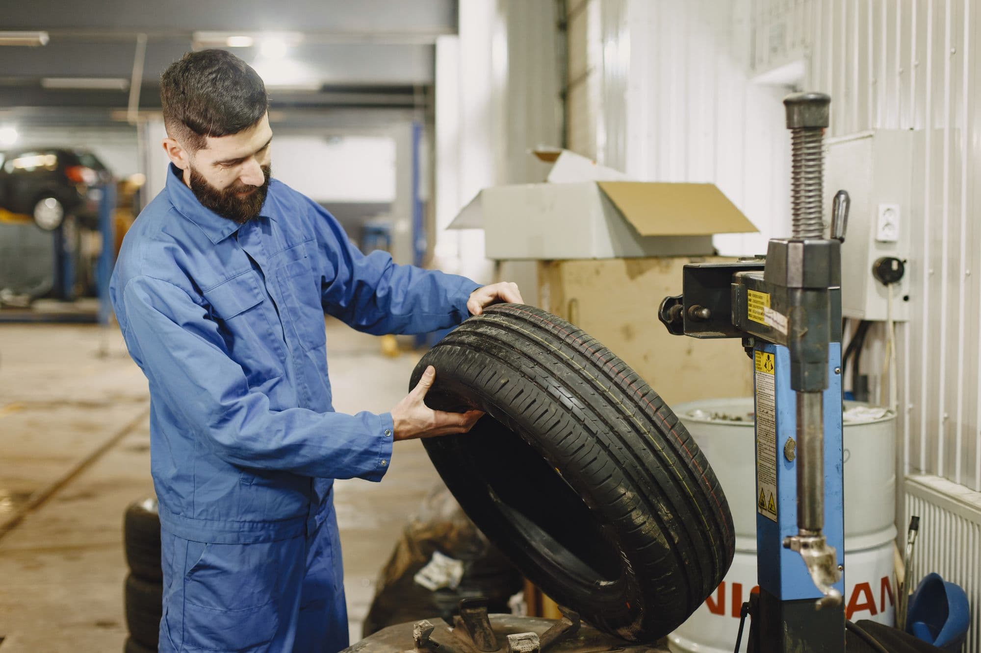 A mechanic carrying a tyre across the workshop