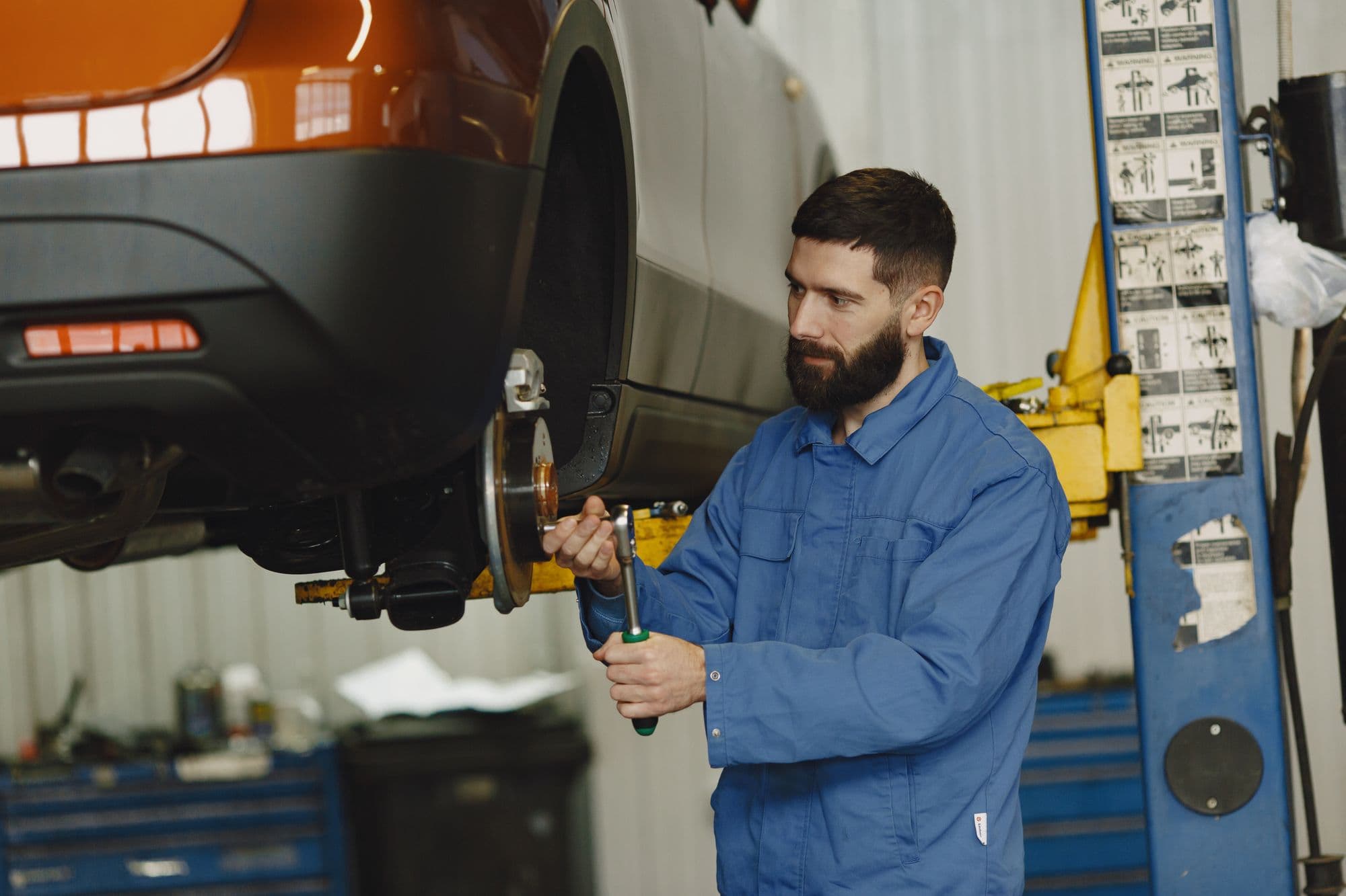 A mechanic working under the chassis of an orange car