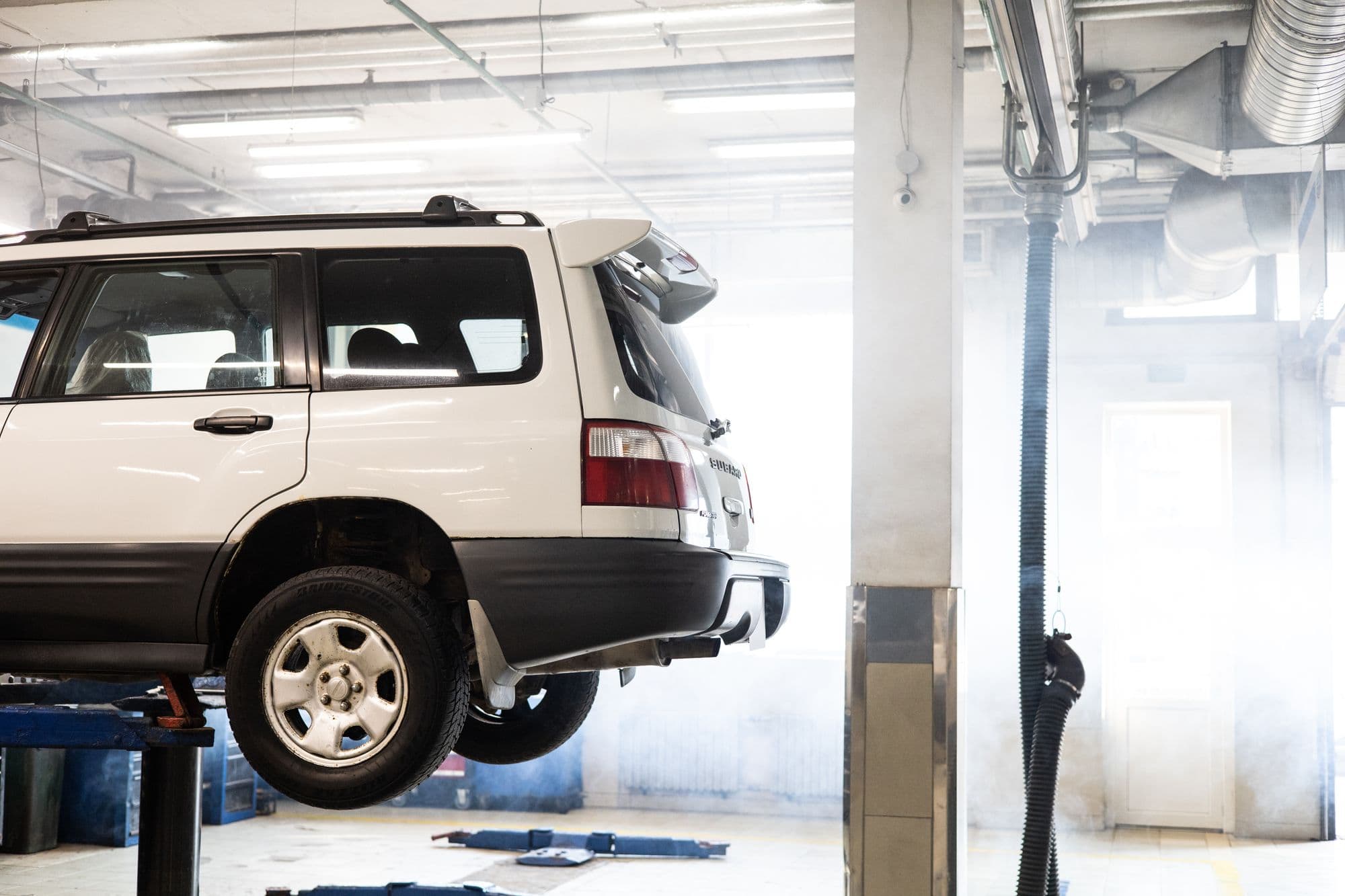 A white SUV raised on a lift in an empty, tidy workshop