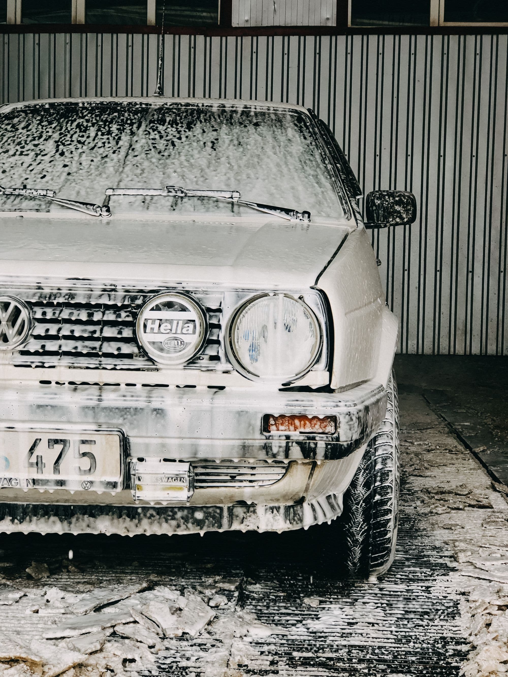 A car being washed with a pressure hose inside a garage