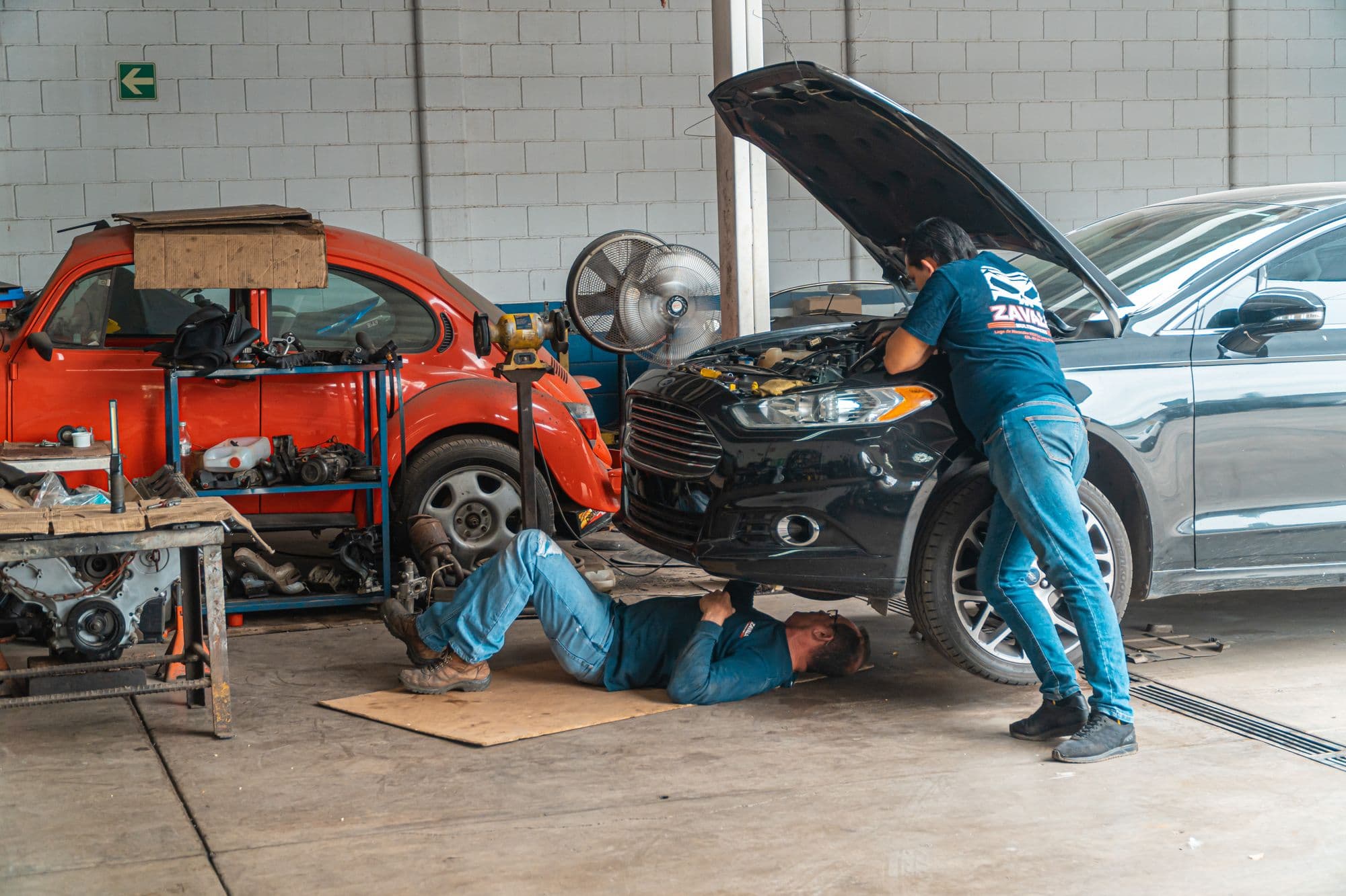 Mechanics working on cars across the workshop floor