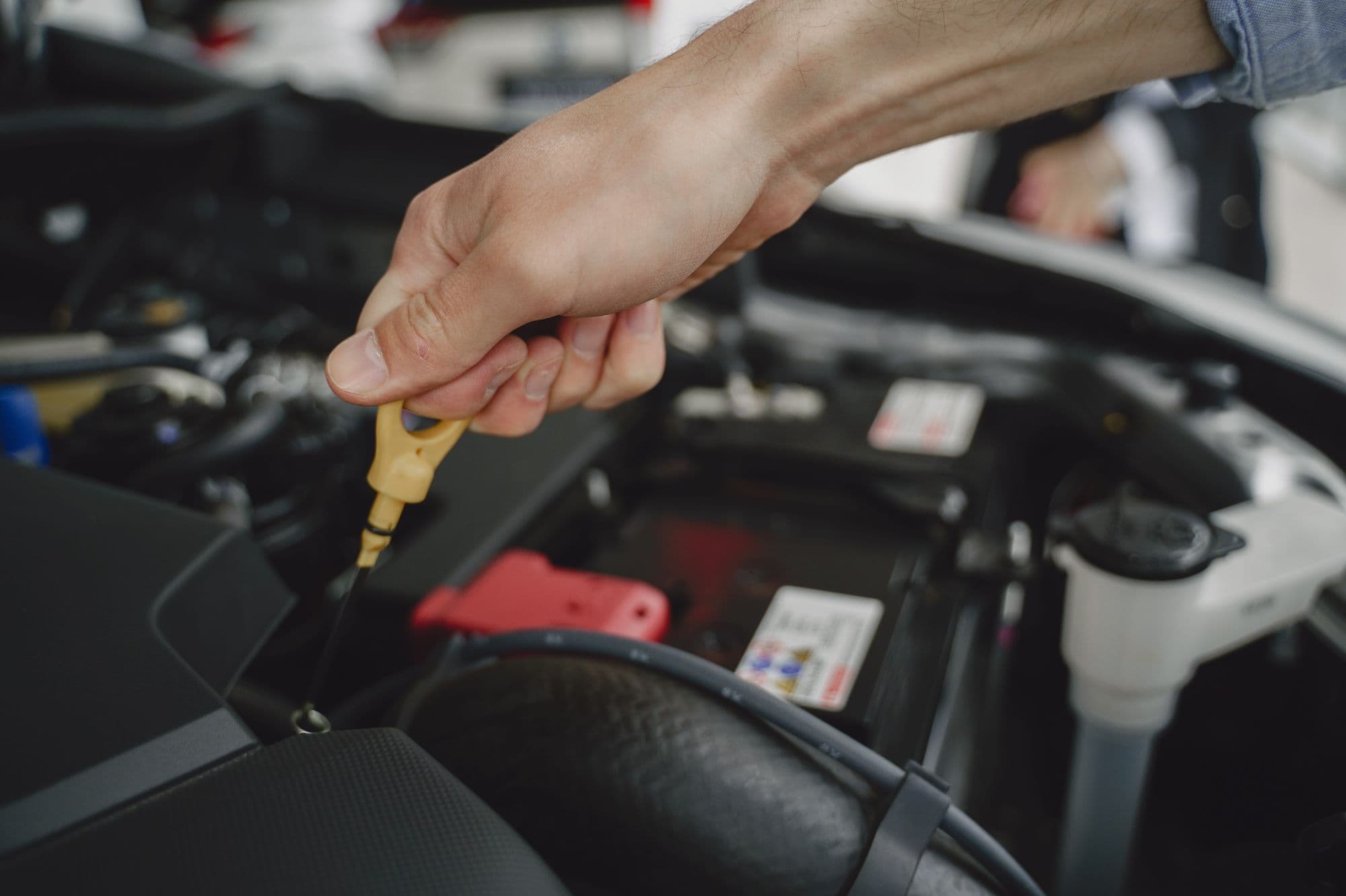 A hand pulling a yellow dipstick from an engine