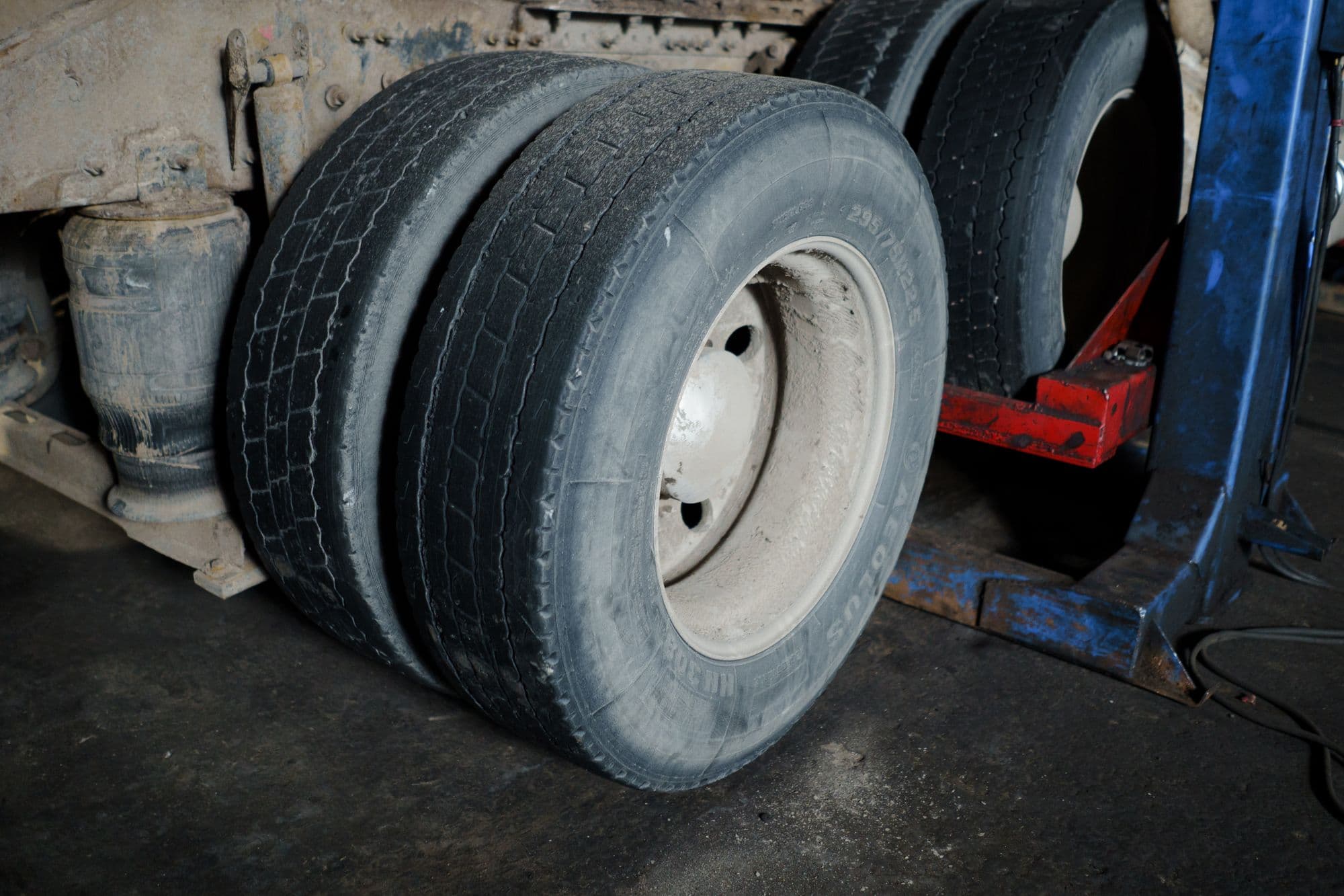 Two worn, dirty tyres on a workshop floor
